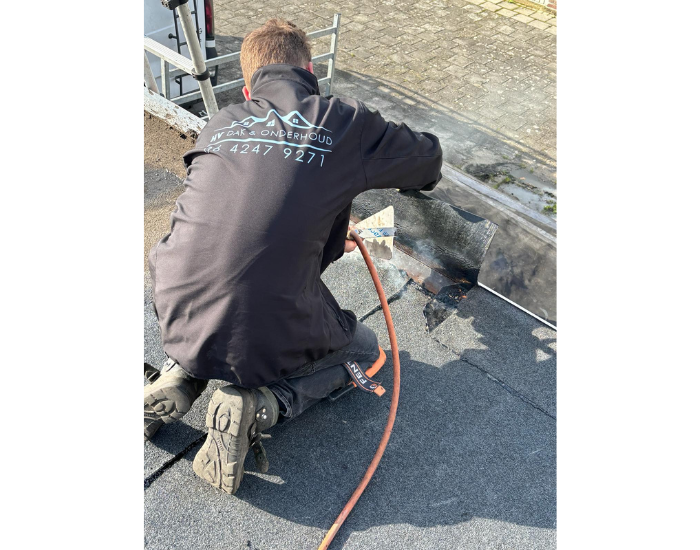 Vakman van HV Dak & Onderhoud brengt nieuwe dakbedekking aan