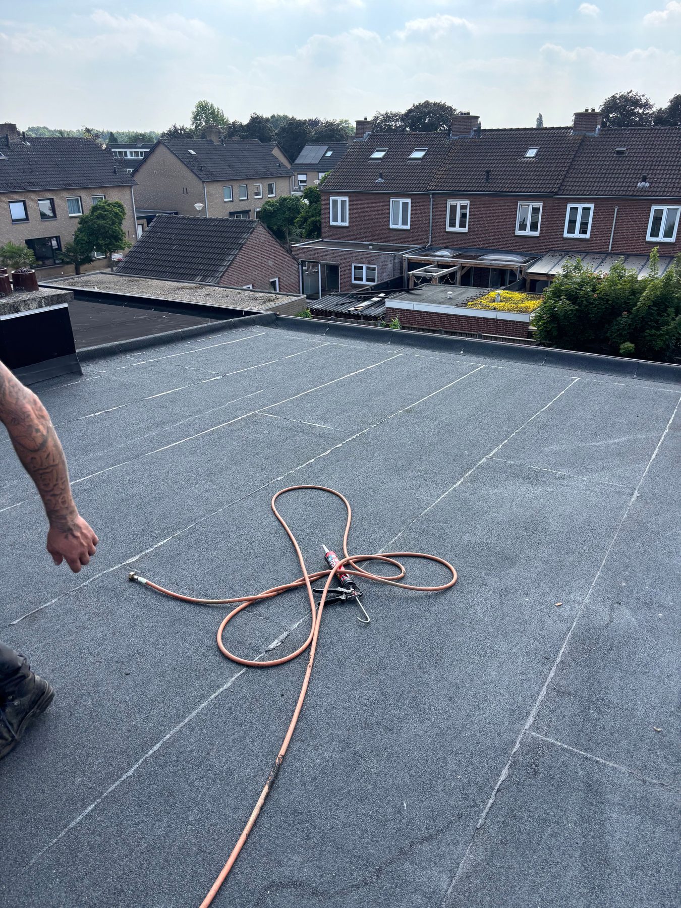 Dakdekker werkt aan een groot plat dak in een woonwijk