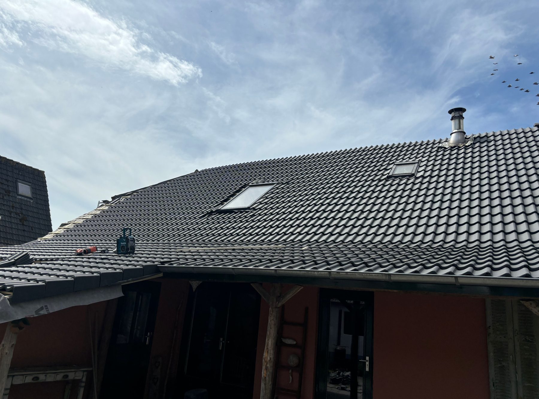 Gerenoveerd pannendak van een woning onder een strakblauwe lucht