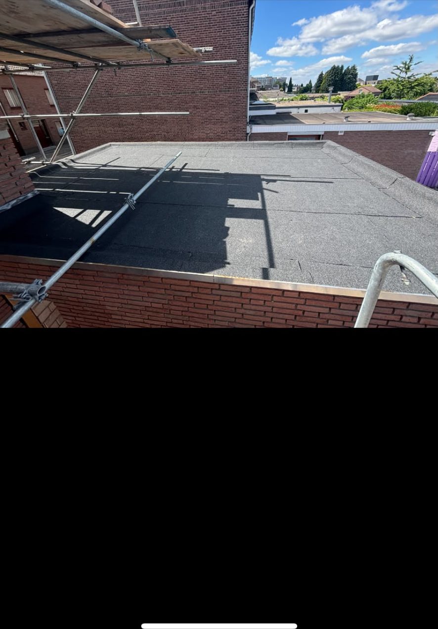 Nieuw bitumen plat dak met steiger langs de gevel van een woning