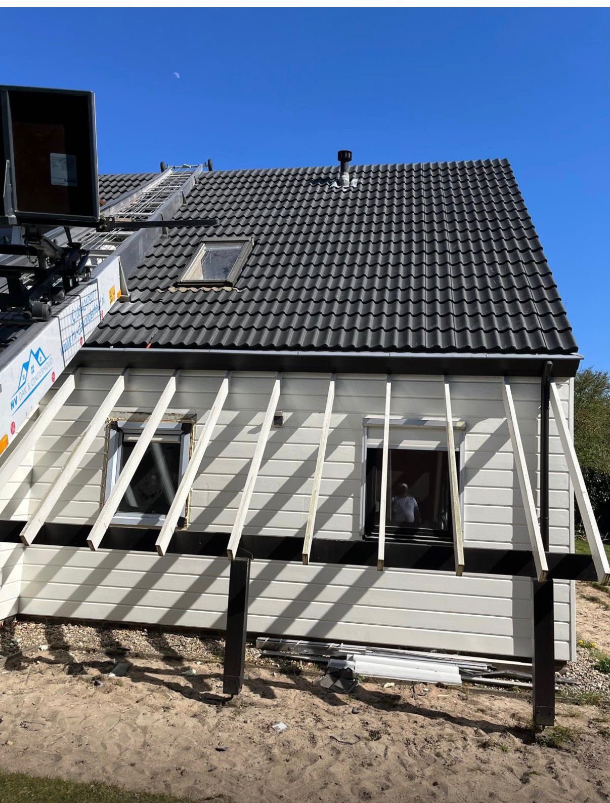 Zwart pannendak en dakkapel in aanbouw met loodwerk en zinken afvoer