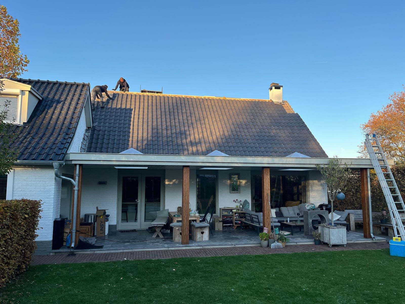 Dakdekkers vervangen het pannendak van een woning met veranda